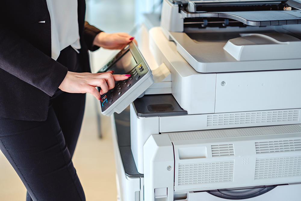 woman using multi-function printer in office