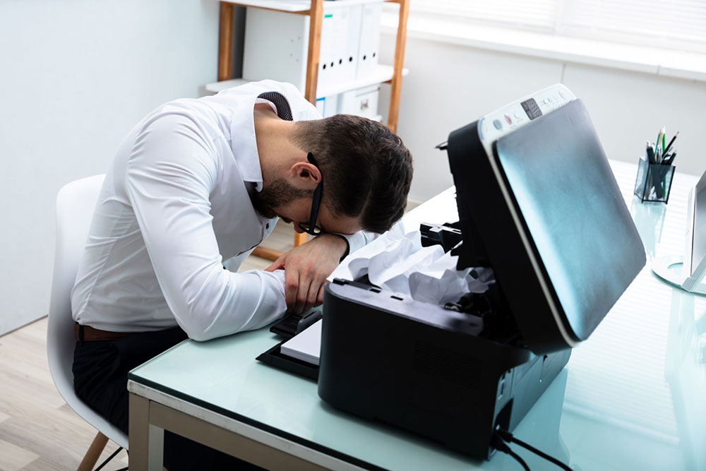 man frustrated with a broken printer